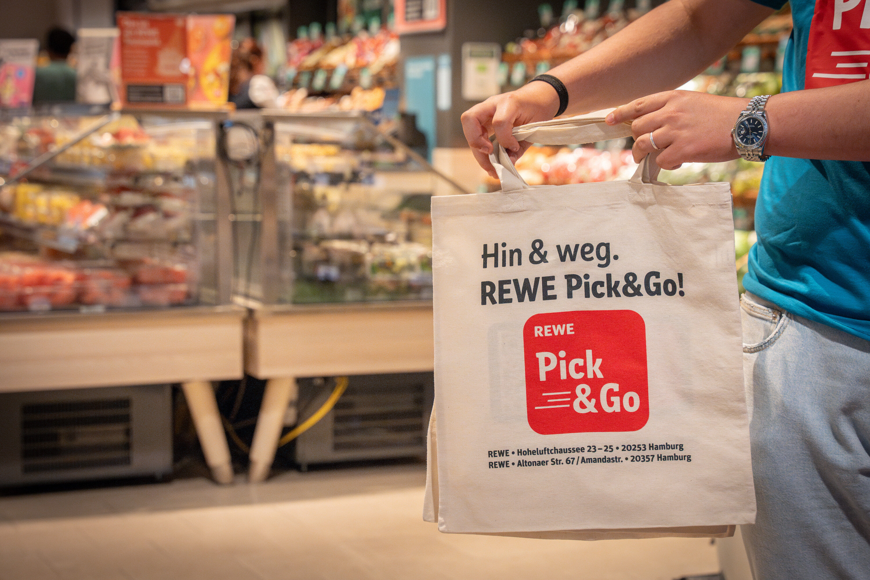 Nahaufnahme von REWE Beutel mit Hin und weg drauf im Markt | © REWE Markt GmbH