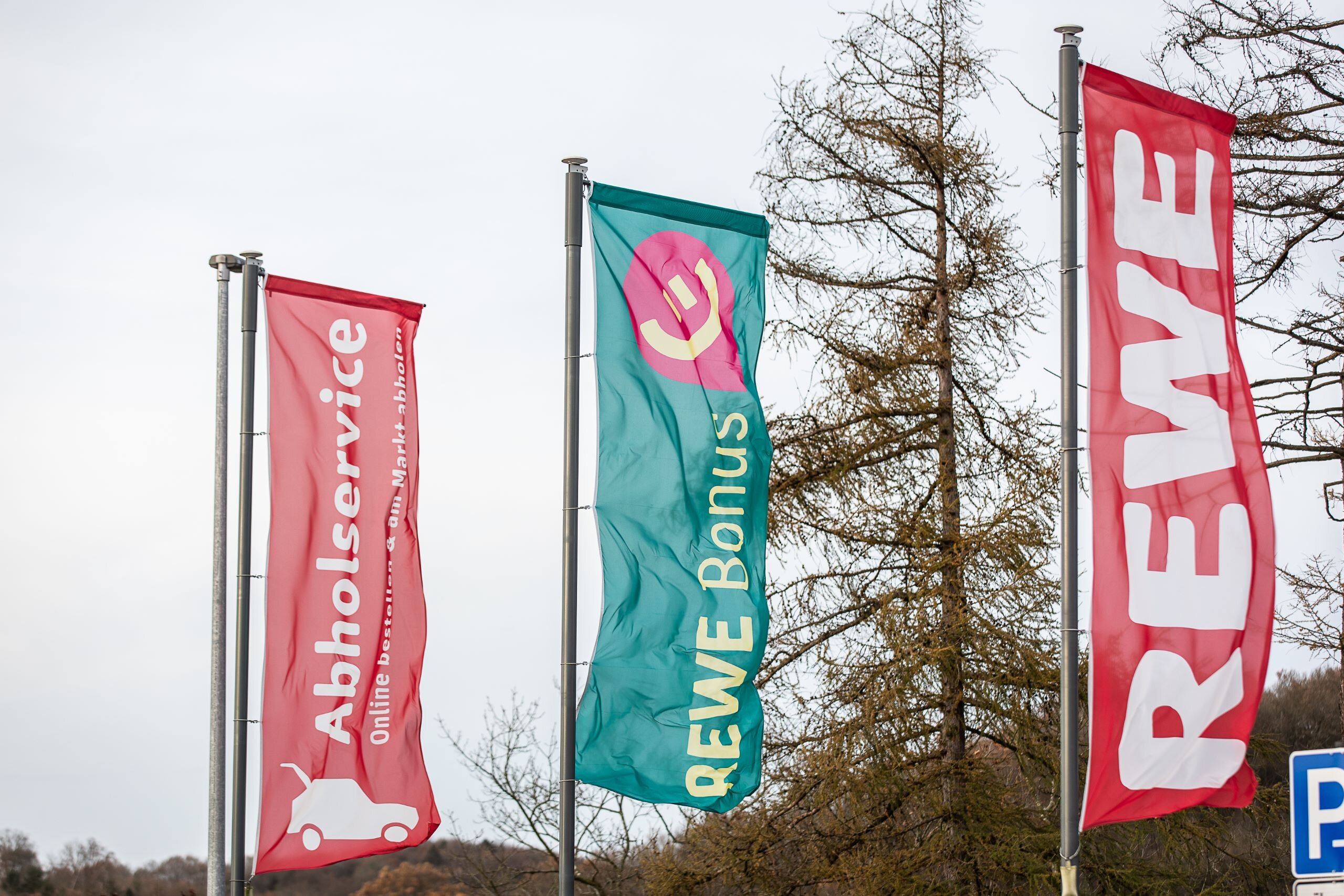 REWE und REWE Bonus Flaggen stehen vor REWE-Markt