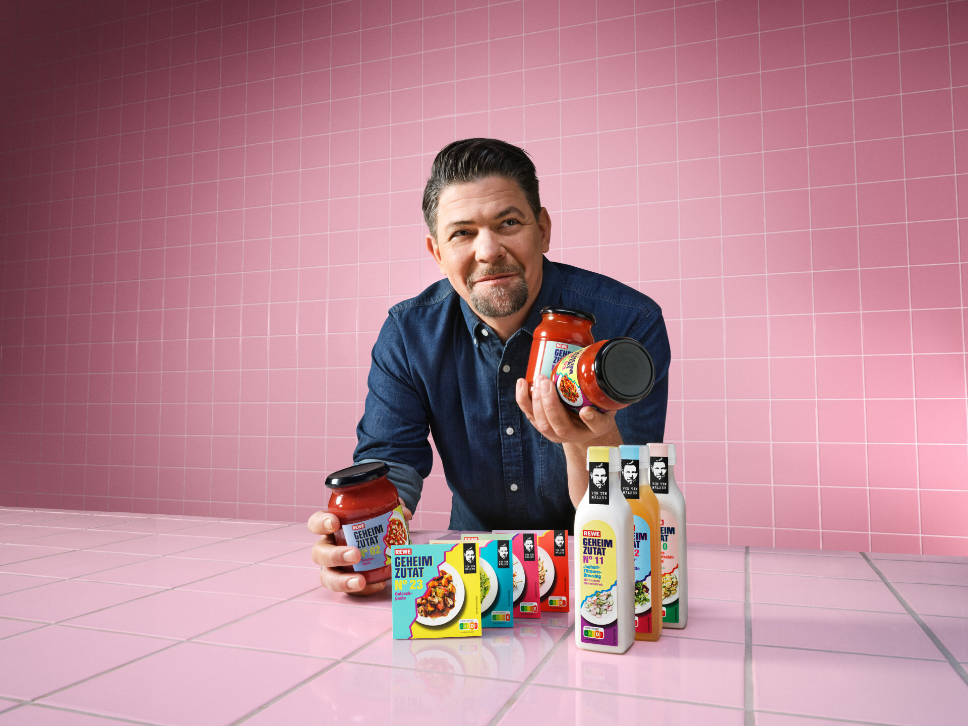Tim MÃ¤lzer hÃ¤lt Produkte aus REWE Kampagne Geheimzutat hoch
