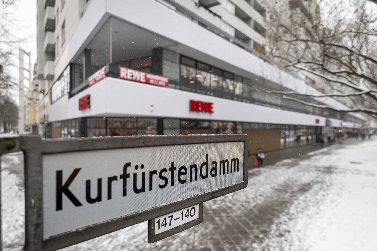 Nahaufnahme von StraÃenschild "KurfÃ¼rstendamm" mit REWE Markt im Hintergrund