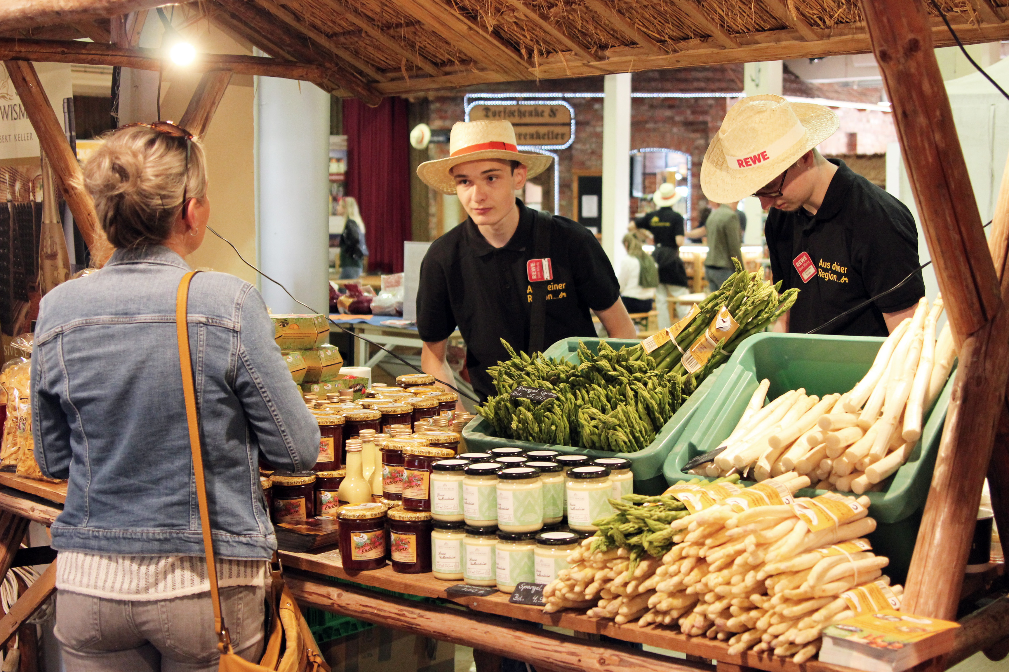 Zwei REWE-Azubis hinter einem Stand mit regionalen Produkten