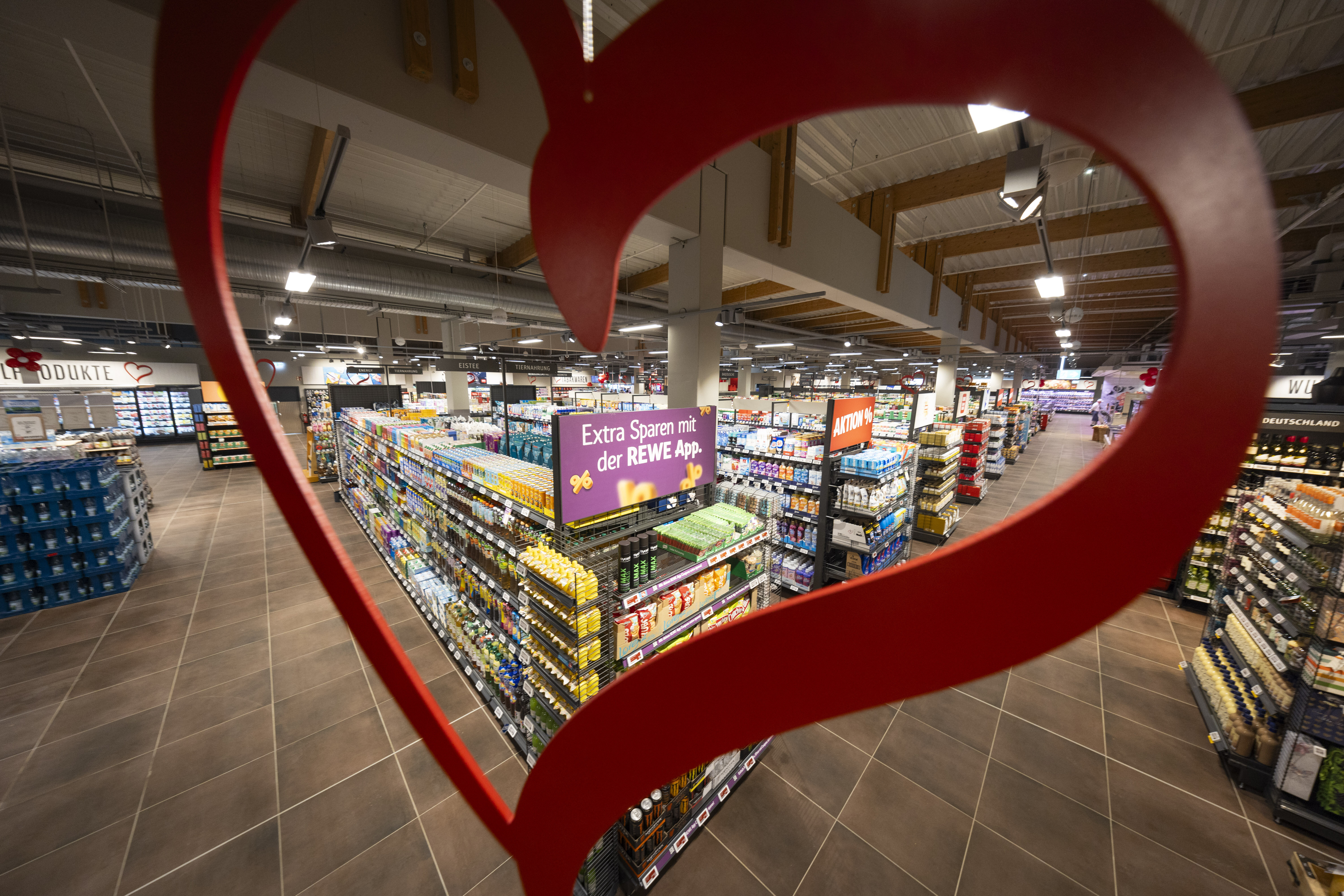 Ein Blick auf die Regale im REWE-Markt durch ein rotes Herz hindurch