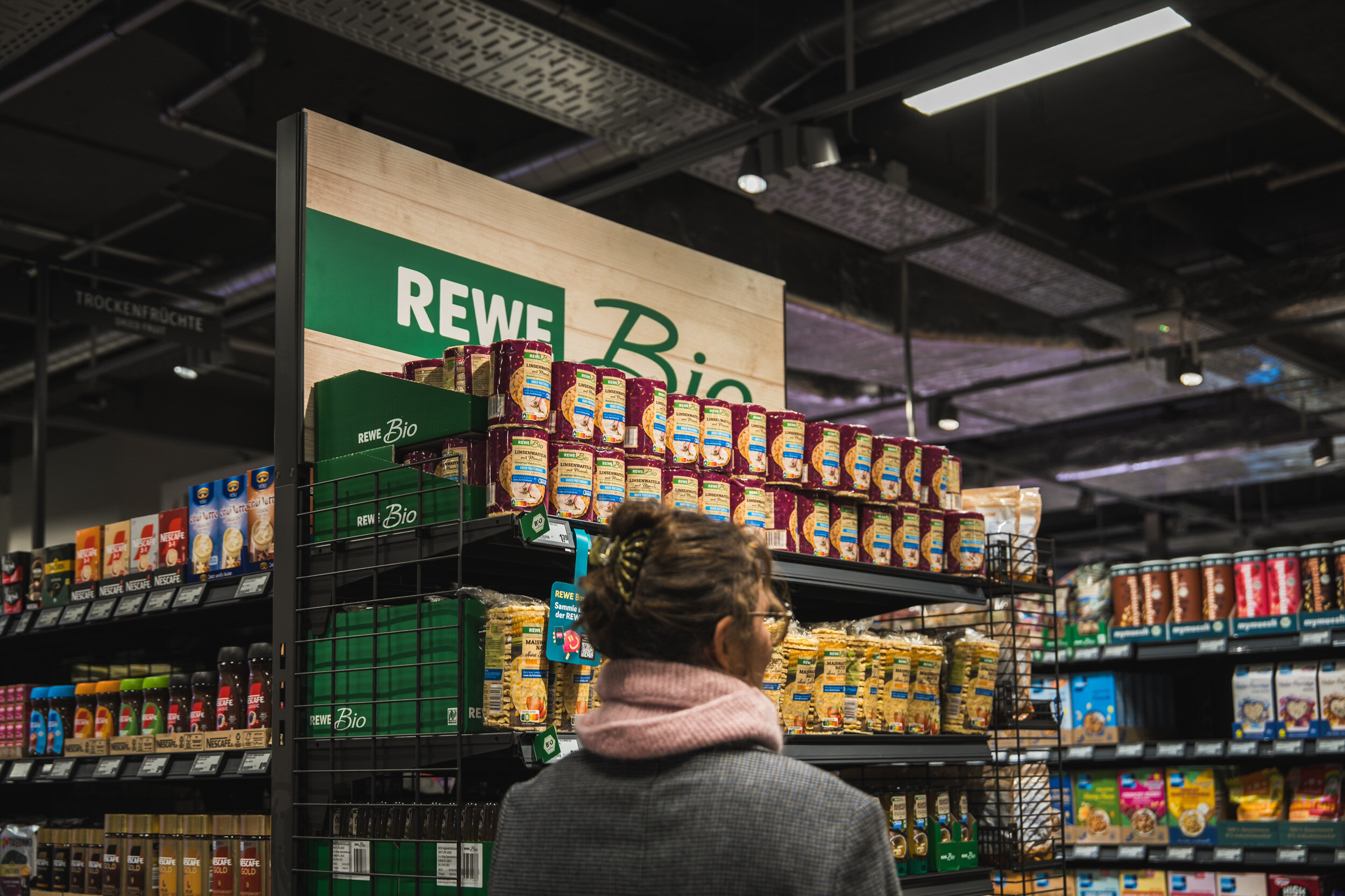 Regal mit Bio-Produkten und Frau im Vordergrund, unscharf