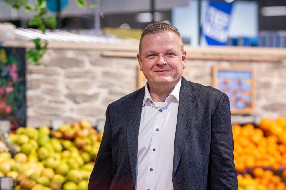 Der Chef des Supermarktes, Björn Keyser, steht in der Obstabteilung und schaut in die Kamera.