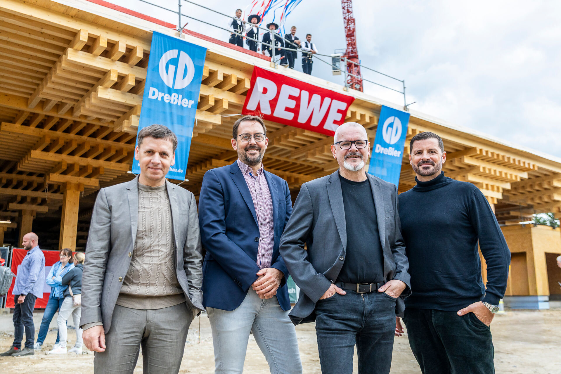 Auf dem Bild stehen vier Männer (v.l. . Friedrich Ludewig (Founding Director, ACME), Florian Nain (Teamleiter Planung & Eigenobjekte Bauwesen, REWE Ost), Klaus Wiens (Head of Bauwesen Filialbau, REWE) Nicolas Leschke (Geschäftsführer, ECF Farmsystems))vor einem sich im Bau befindlichen Supermarkt.