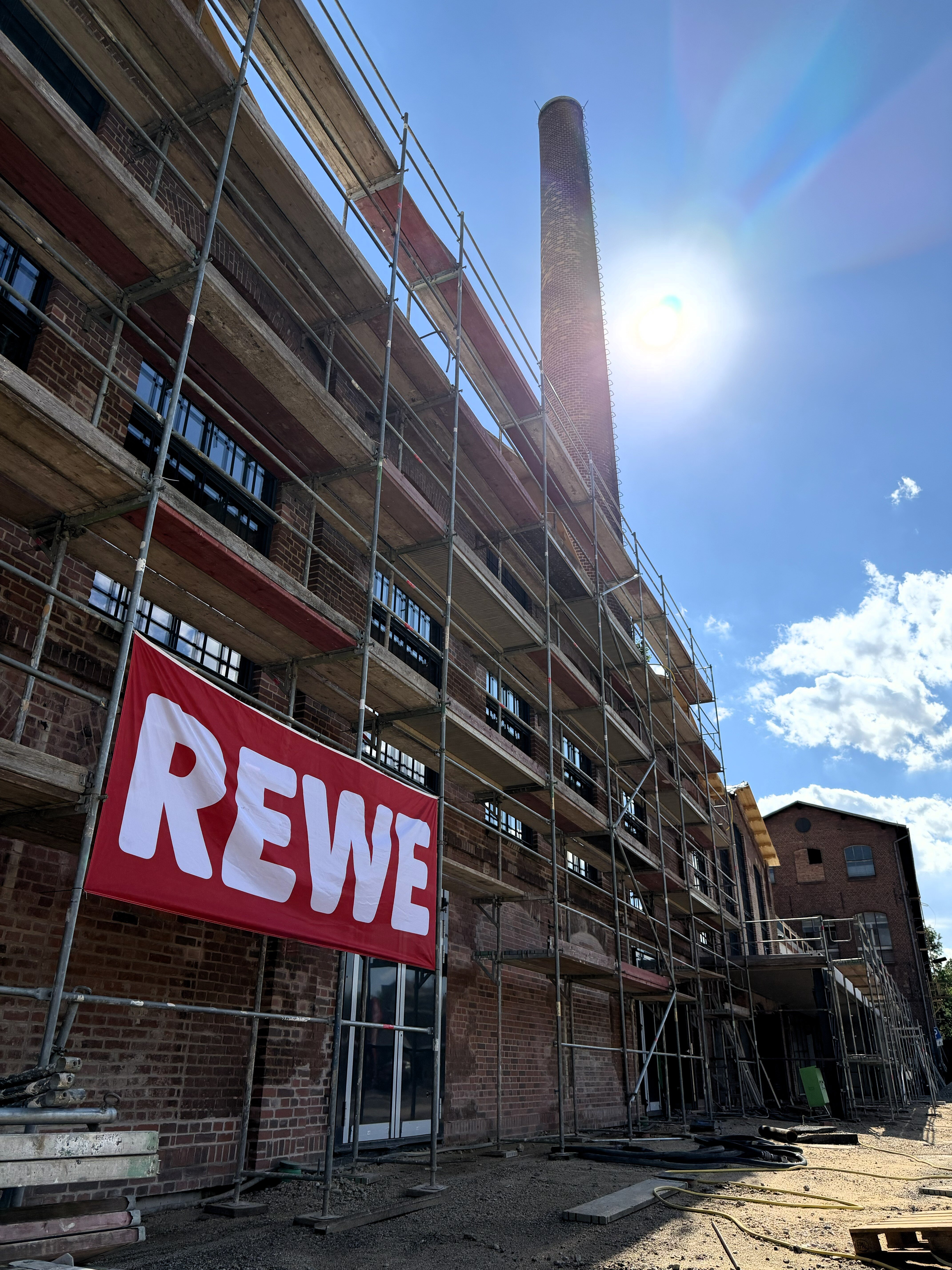 Historische Fassade des Waggonbau-Werks mit Baugerüst und REWE-Transparent