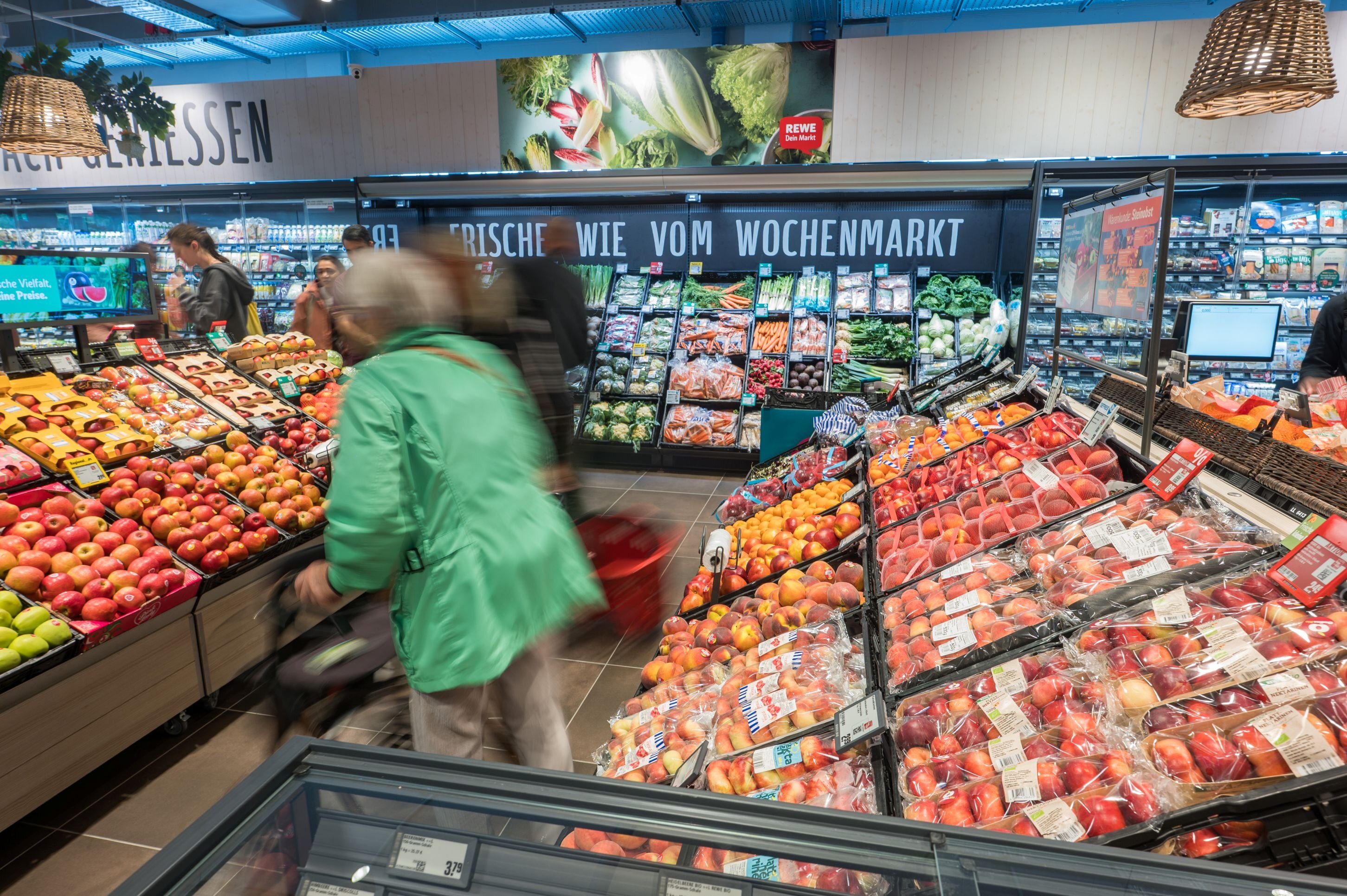 Ein Blick in eine belebte Obst- und Gemüseabteilung eines REWE-Marktes