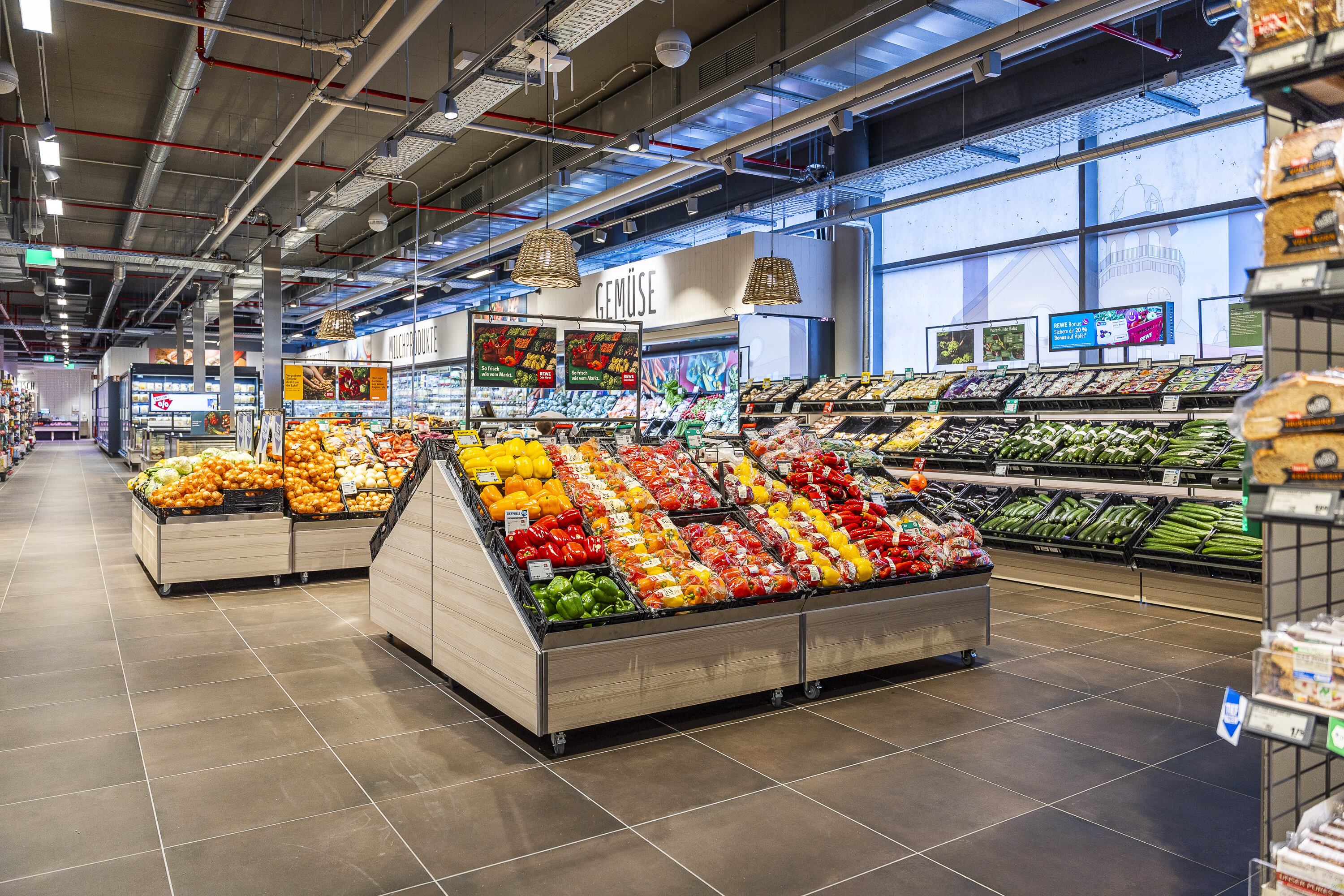 Regale mit Obst und Gemüse in einem REWE Markt. 