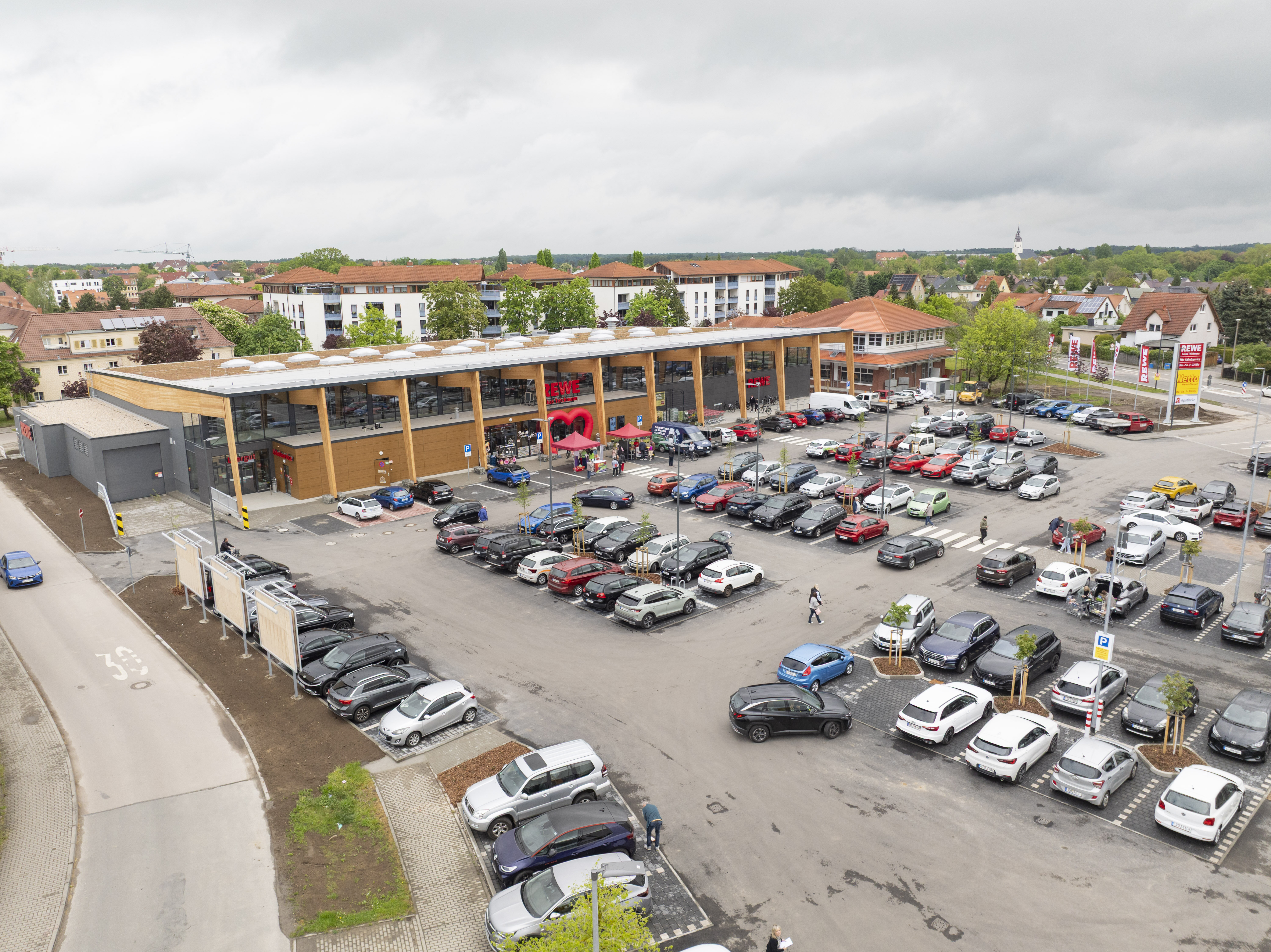 Der REWE-Markt in Taucha von oben mit Parkplatz und Straße fotografiert