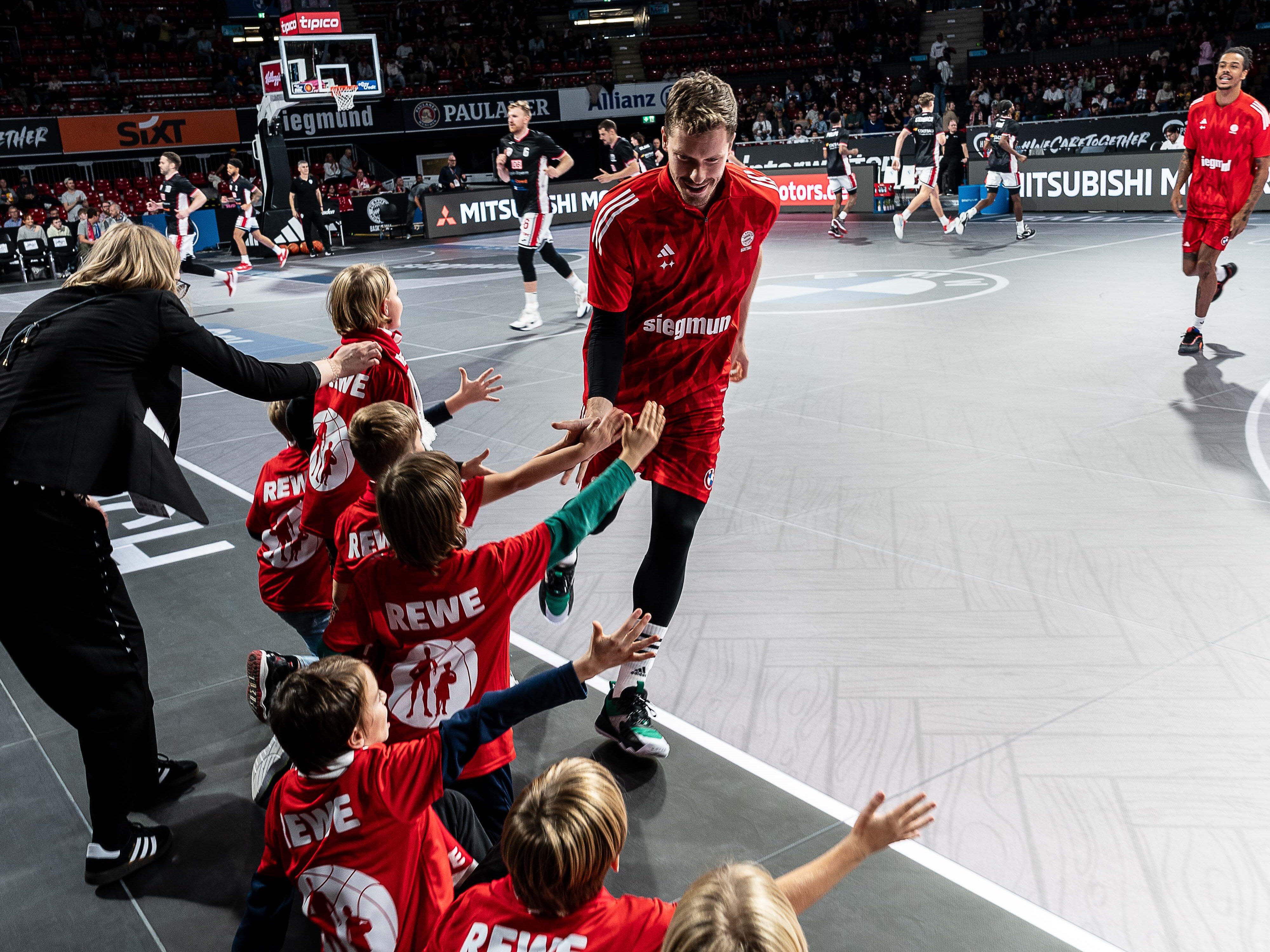 Kinder an Speilfeldrand geben Basketballer High Five