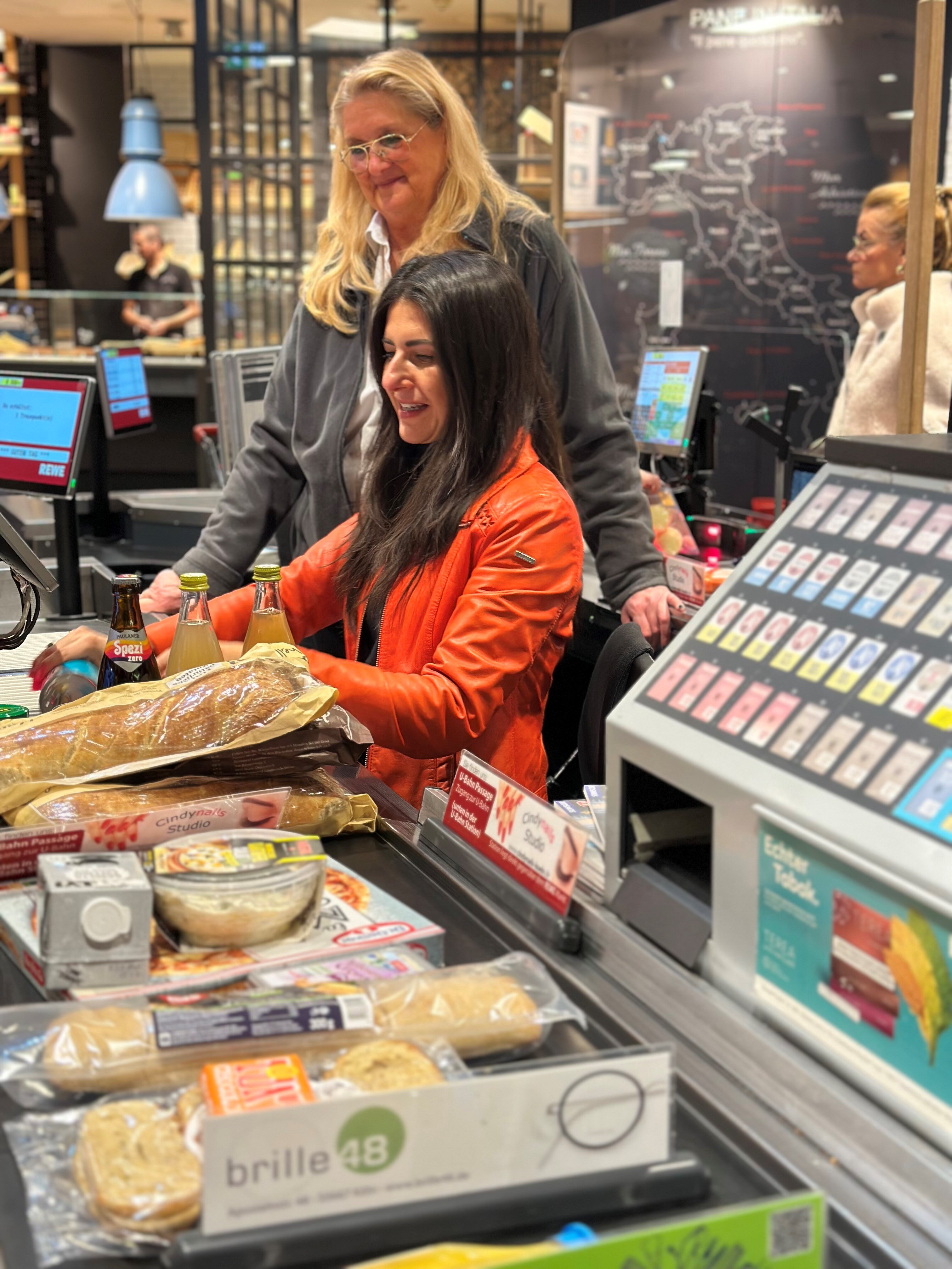 Die Bundestagsabgeordnete Serap Güler kassiert Produkte an einer REWE Kasse