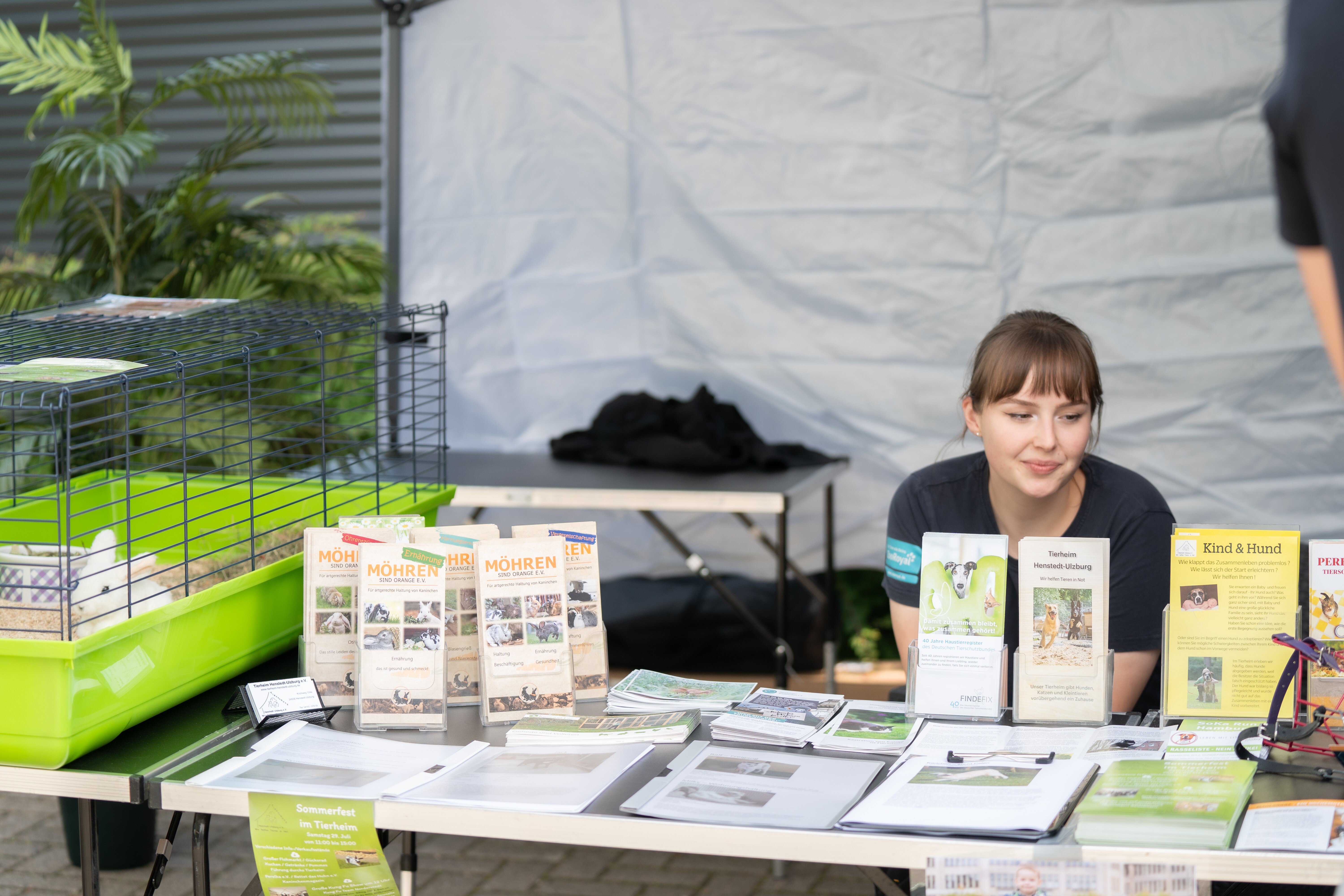 Frau sitzt hinter Infostand